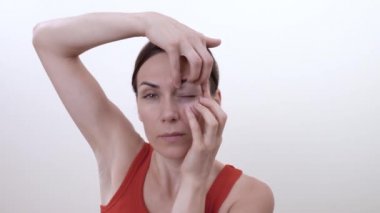 Kırışıklık göz köşelerde kurtulmak için egzersiz yaparak gülümseyen esmer kız portresi. Beyaz arka plan üzerinde izole.