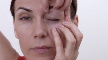 Esmer kız yüz göz çevresi kaz ayağı kurtulmak için egzersiz yaparak gülümseyen kapatın. Beyaz arka plan üzerinde izole.