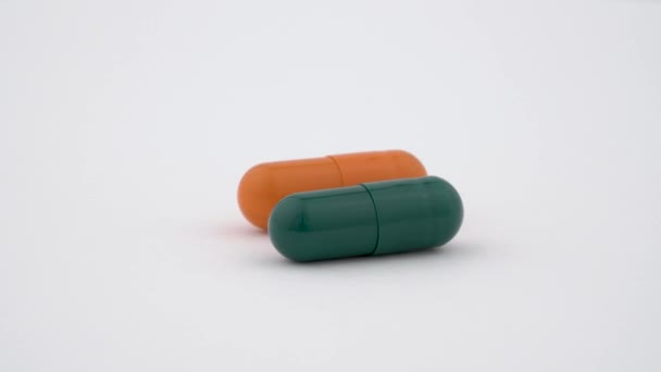 Deux capsules d'amidon dur tournant sur la platine tournante. Couleur orange et verte. Isolé sur fond blanc. Fermer macro .