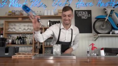 Yakışıklı bir genç barmen bardaki buz küpleri ile bir bardak içine blue curacao içki dökülen sayaç.