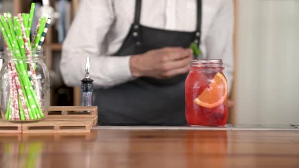 Close-up de um belo jovem barman mãos terminando de fazer um fresco, limonada cor vermelha fresca no balcão do bar . — Vídeo de Stock