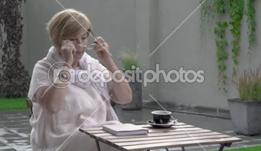 Güzel bir yaşlı kadın terasta açık havada duruyor. O gözlüklerini alıyor ve bir kitap okuma başlar.