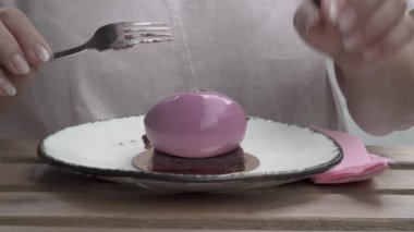 Yakın çekim ön planda bir kadın tarafından yenilen bir pasta. Bir kadın eli bir çikolata üst alır, peçete eliyle mendil, çatal ile çok kolay fişleri.