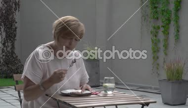 Yaşlı bir kadın bir pasta yemeye tamamlanır. Terasta yer dışında oturuyor. O dudaklarını mendil ve daha sonra bazı suyu içer