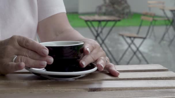 As mãos de uma mulher de close-up boneca tomando uma xícara de chá da mesa. Chuva forte no fundo — Vídeo de Stock