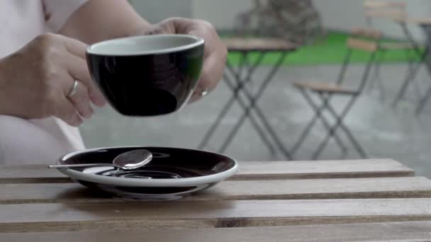 Primer plano de las manos femeninas mientras bebe té. Está lloviendo mucho en la terraza. — Vídeos de Stock