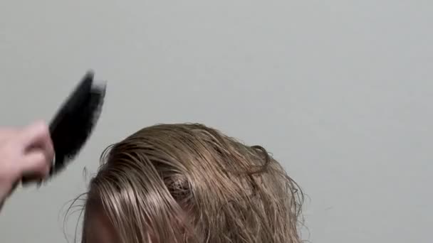 De kapper droogt blonde haren met een föhn en een haren borstel. Closeup. — Stockvideo