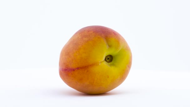 Eine Pfirsichfrucht rotiert auf dem Plattenteller, isoliert auf weißem Hintergrund. Nahaufnahme. — Stockvideo
