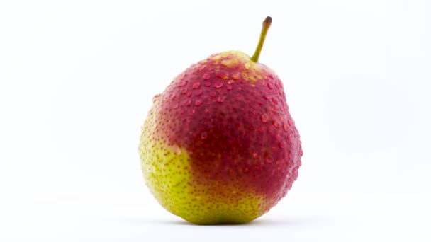 En päron frukt i vattendroppar roterar på skivtallriken. Isolerad på den vita bakgrunden. Närbild. Makro. — Stockvideo