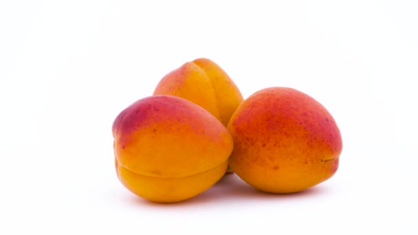 Three apricot fruits rotating on the on the turntable isolated on the white background. Close up. Macro. — Stock Video