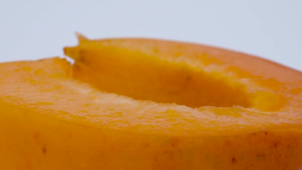 Super estrecha macro de la mitad de la fruta de albaricoque. Girando en el tocadiscos. Aislado sobre el fondo blanco . — Vídeos de Stock