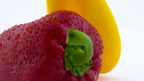 超级特写宏的两个甜辣椒-黄色和红色的水滴。在转盘上旋转。在白色背景上被隔离. — 图库视频影像