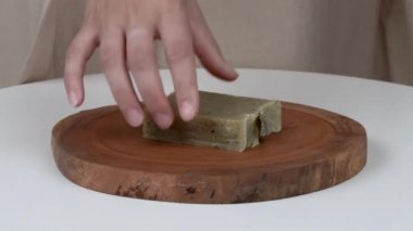 Kadının bir close-up bir yuvarlak ahşap tepsi doğal lavanta sabun koyarak çubuklar eller. Üstündeki o iki çubuklarıyla lavanta ve okaliptüs koyar.