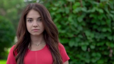 Bir close-up çekici bir genç kadın, hala ayakta ve kameraya bakıyor. Çok ciddi görünüyor ve sonra gülümseyerek ve gülmeye başladı.