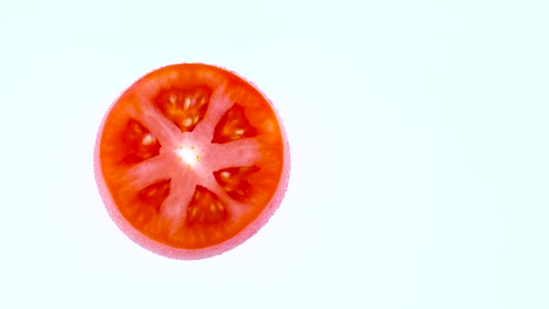 Half frame of a top view from above of a cross section of red tomato. Rotating on the turntable isolated on the white background. Close-up. Macro. — Stock Video