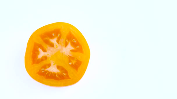 Mezza struttura di una vista superiore dall'alto di un taglio in pomodoro giallo metà arancione. Ruotando sul giradischi isolato sullo sfondo bianco. Primo piano. Macro . — Video Stock