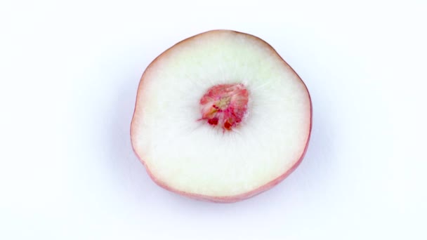 Top view from above. One half of a doughnut flat peach with a pit. Rotating on the turntable isolated on the white background. Close-up. Macro. — Stock Video