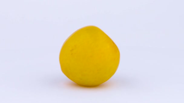 Eine ganze große gelbe Pflaume auf dem Plattenteller. Wassertropfen erscheinen während der Rotation auf der Haut. isoliert auf weißem Hintergrund. Nahaufnahme. Makro. — Stockvideo