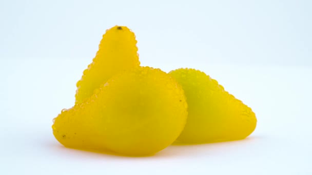 Macro shoot of a three small yellow pear tomatoes with water drops. Rotating on the turntable. Isolated on the white background. Close-up. — Stock Video