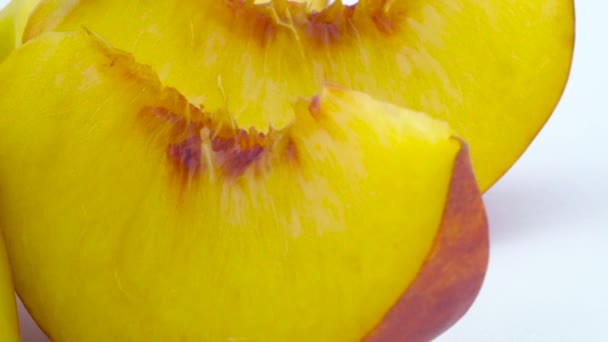 Makro-fotografering av mogen persika skivor. Långsamt roterande på skivtallriken isolerat på den vita bakgrunden. Närbild. — Stockvideo