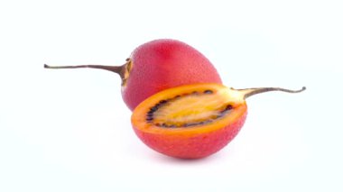Bir buçuk olgun tamarillo meyve suyu ile bırakır. Beyaz arka plan üzerinde izole pikap üzerinde hızlı bir şekilde döner. Yakın çekim. Makro.