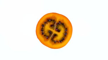 Makro çekim. Bir olgun tamarillo meyve dilim üstten görünüm yukarıdan. Kesit. Beyaz arka plan üzerinde izole pikap üzerinde döner. Yakın çekim.