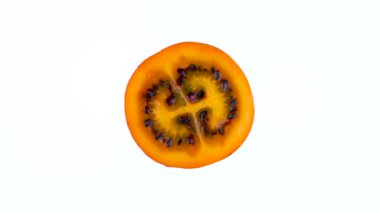 Makro çekim. Olgun tamarillo meyve bölümü su ile yukarıdan üstten görünüm bırakır. Kesit. Beyaz arka plan üzerinde izole pikap üzerinde döner. Yakın çekim.