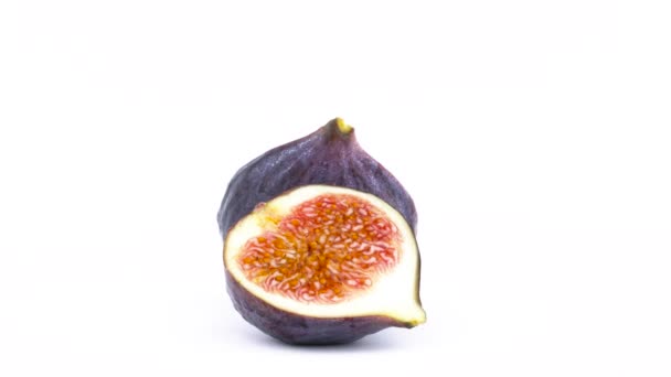 Två halvor av mogen gemensamma fig frukt med vatten droppar. Långsamt roterande på skivtallriken isolerat på den vita bakgrunden. Närbild. Makro. — Stockvideo