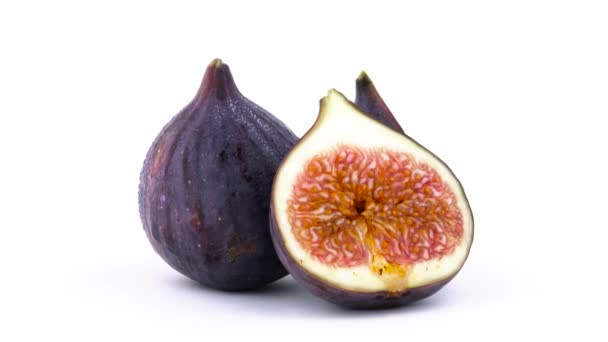 En helhet och två halvor av mogen gemensamma fig frukt med vattendroppar. Långsamt roterande på skivtallriken isolerat på den vita bakgrunden. Närbild. Makro. — Stockvideo