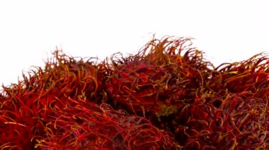 Kırmızı renk rambutan meyve yığın üst kısmı makro çekim. Beyaz arka plan üzerinde izole pikap üzerinde yavaş yavaş döner. Yakın çekim.