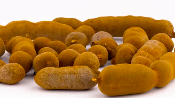 Closeup of a heap of tamarind fruit pods rotating on the turntable. Isolated on the white background. Macro. — Stock Video