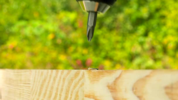 Fechar a chave de fenda elétrica desaparafusar um parafuso auto-roscante preto na prancha de madeira. Ao ar livre. Espaço de cópia . — Vídeo de Stock