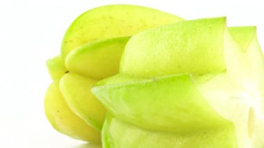 Makro çekim carambola yarısı su damlaları ile bir bütün ve bir meyve. Beyaz arka plan üzerinde izole pikap üzerinde yavaş yavaş döner. Yakın çekim.