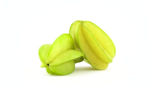 Dos frutas enteras de carambola con gotas de agua. Girando sobre el plato giratorio aislado sobre el fondo blanco. De cerca. Macro . — Vídeos de Stock