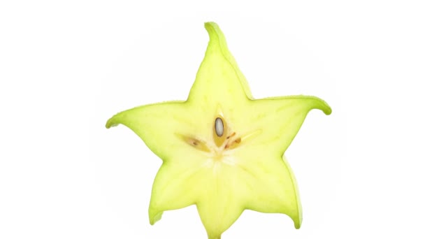 One star shaped slice of ripe carambola fruit with water drops. Slowly rotating on the turntable isolated on the white background. Close up. Macro. — Stock Video