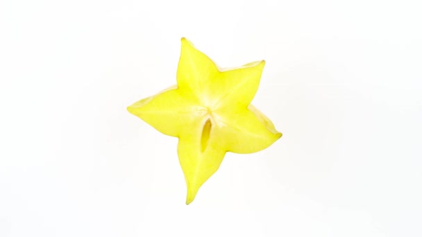 Ovanifrån från ovan av en stjärna formad skiva mogna carambola frukt. Tvärsnittet. Långsamt roterande på skivtallriken isolerat på den vita bakgrunden. Närbild. Makro. — Stockvideo