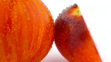 Bir bütün kırmızı küre makro çekim şeritli domates ve bir yarı beyaz arka plan üzerinde izole pikap üzerinde yavaş yavaş dönen Indigo gül domates.