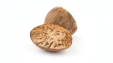 Soyulmuş nutmegs (yatay ve dikey kesim) iki yarısı. Beyaz arka plan üzerinde izole pikap üzerinde yavaş yavaş döner. Yakın çekim. Makro.