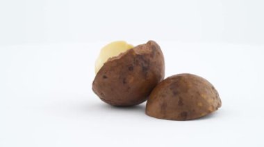 Kabuk ve çekirdek ile kırık macadamia nut. Beyaz arka plan üzerinde izole pikap üzerinde hızlı bir şekilde döner. Yakın çekim. Makro.
