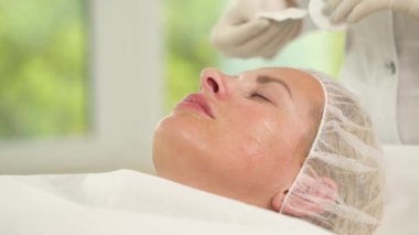 Kadının yüzüne yan görünüm yakından, pamuk tamponlarla eldivenlerle elinde iki yüzü temiz.