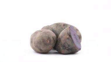 İki bütün mor patates ve yarım saniyeden vitelotte patates. Beyaz arka plan üzerinde izole pikap üzerinde döner. Yakın çekim. Makro.