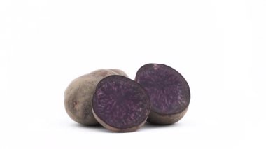 Bir bütün noire patates, bir yarı mor patates ve bir dilim. Beyaz arka plan üzerinde izole pikap üzerinde yavaş yavaş döner. Yakın çekim. Makro.
