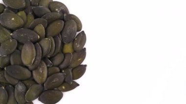 Yukarıdan görüntüleyin. Yarım daire parçası kabak çekirdeği yığın şeklinde. Beyaz arka plan üzerinde izole pikap üzerinde yavaş yavaş döner. Yakın çekim. Makro. Kopya alanı.
