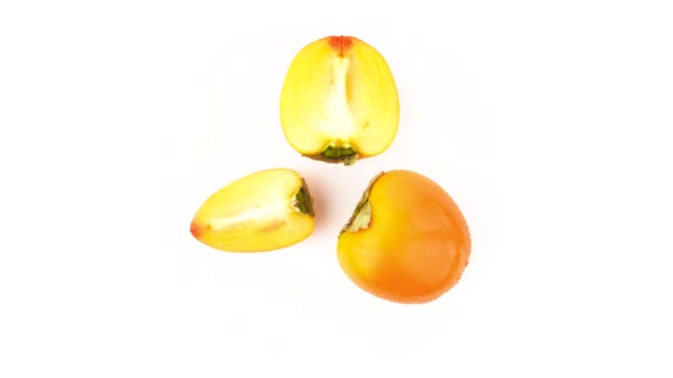 从上面看一个柿子果与两个柿子半。水滴。旋转。在白色背景上隔离。特写。宏观. — 图库视频影像