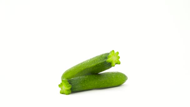 Två baby grön zucchini med vattendroppar. Roterande på skivtallriken. Isolerad på den vita bakgrunden. Närbild. Makro. — Stockvideo