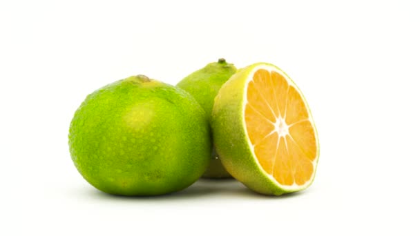 Dos frutos de mandarina verdes enteros y medio cortados con gotas de agua. Girando en el tocadiscos. Aislado sobre el fondo blanco. Primer plano. Macro . — Vídeo de stock