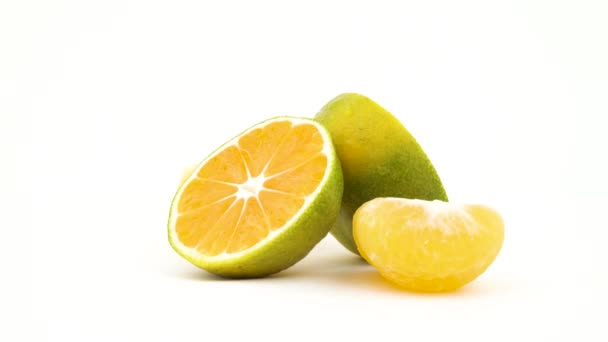 Dos mitades de una mandarina verde con gotas de agua. Rodajas de mandarina verde girando. Aislado sobre el fondo blanco. Primer plano. Macro . — Vídeos de Stock