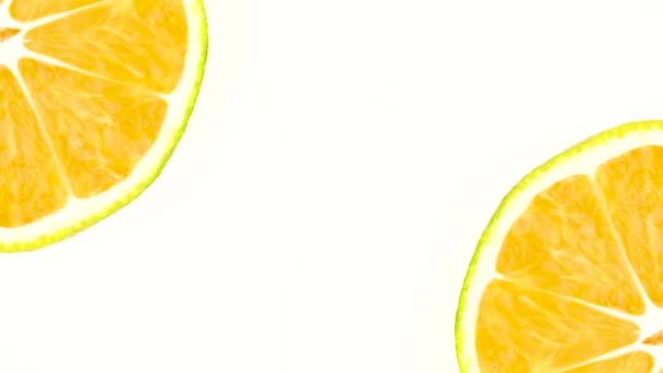 Deux sections transversales d'une mandarine verte tournent dans deux coins du cadre. Isolé sur le fond blanc. Gros plan. Macro .