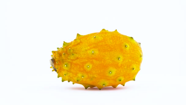 Close-up opnames van een hele kiwano groenten langzaam op tafel zet draait. Geïsoleerd op de witte achtergrond. Macro. — Stockvideo