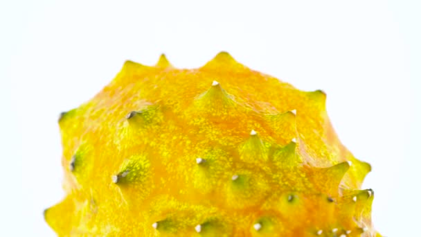Macro shooting of upper part of ripe kiwano fruit. Slowly rotating on the turntable isolated on the white background. Close-up.
